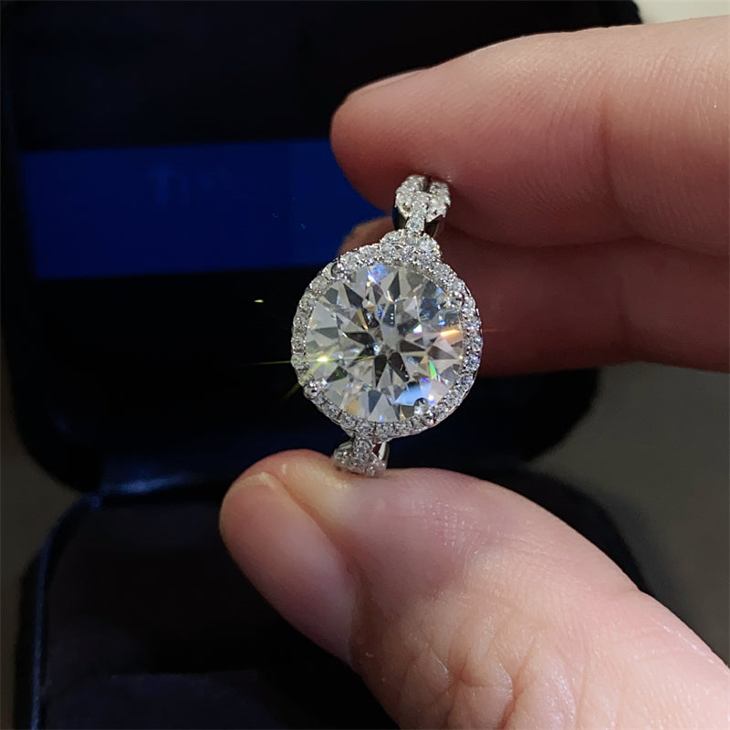 A 925 sterling silver ring with a central moissanite stone surrounded by smaller accent stones, 
