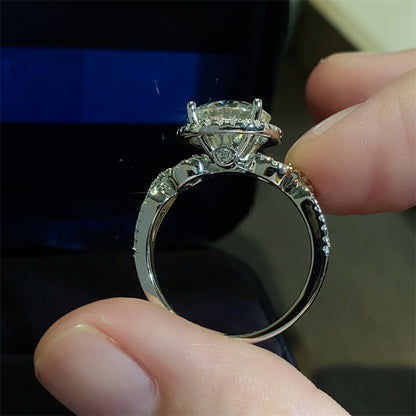 A 925 sterling silver ring with a central moissanite stone surrounded by smaller accent stones, 