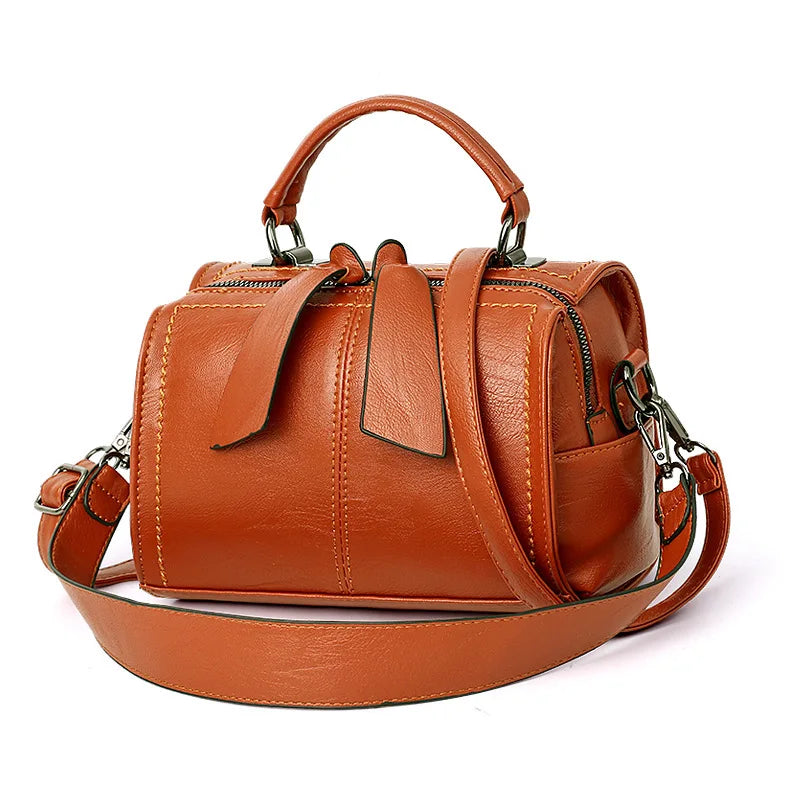 Brown leather handbag with a shoulder strap on a white background