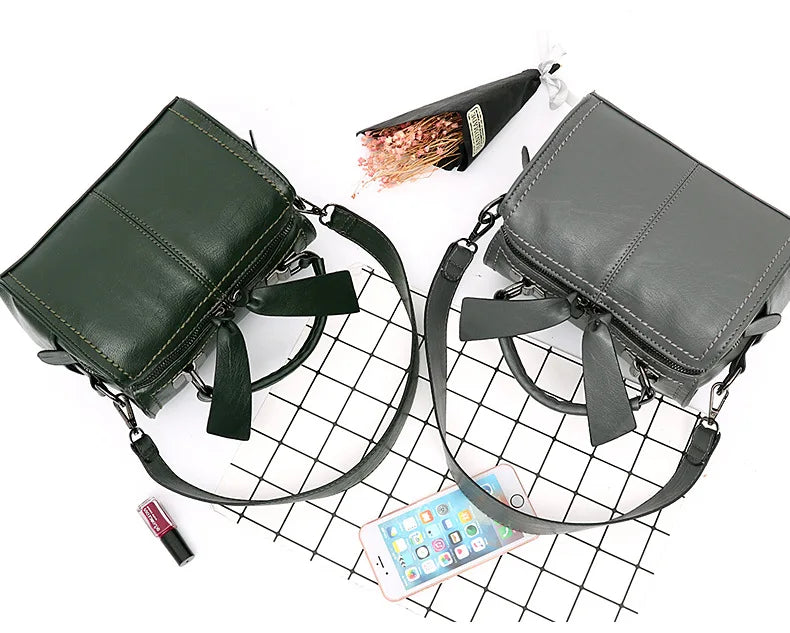 Two handbags, one green and one gray, on a grid background with a phone and lipstick.