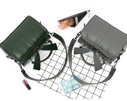 Two handbags, one green and one gray, on a grid background with a phone and lipstick.