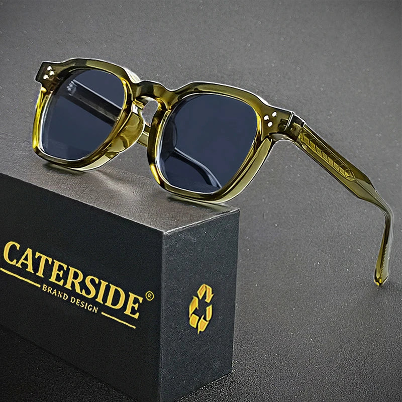 Gold-framed sunglasses on a gray surface with 'Caterside' branding.